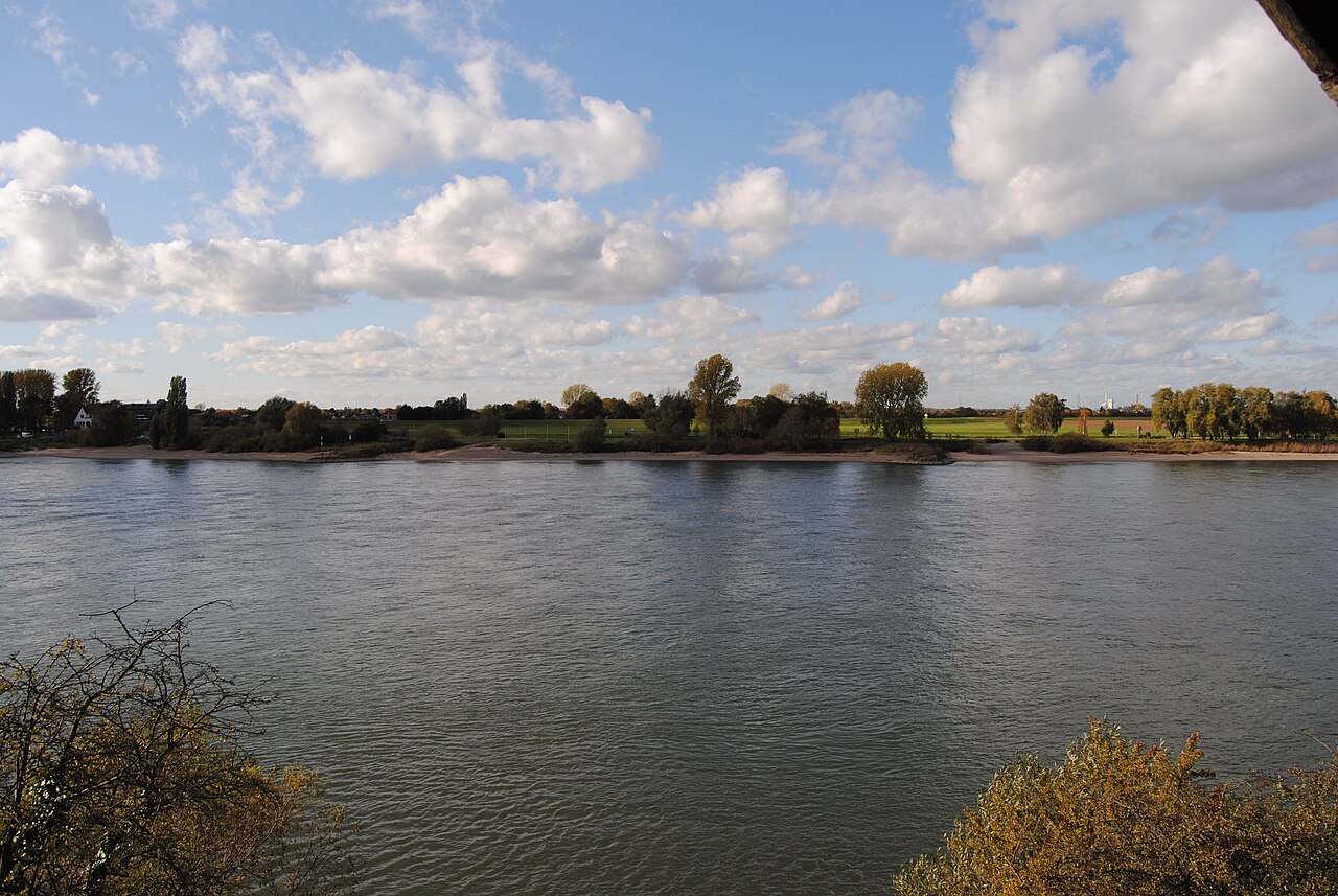 Der Rhein bei Düsseldorf-Kaiserswerth an einem sonnigen Herbsttag mit Wolken über dem flachen Ufer