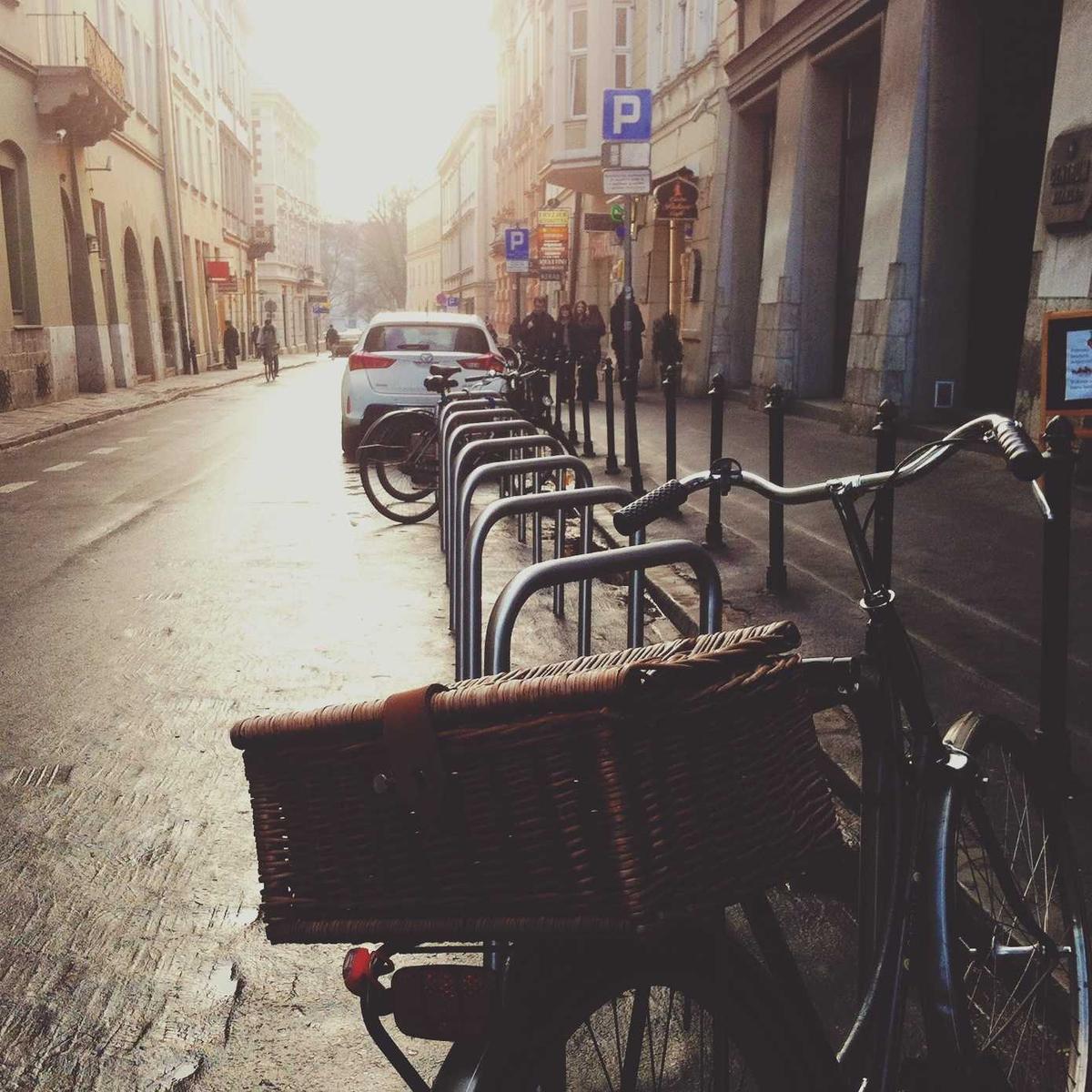 Fahrrad mit Weidenkorb an einem Radständer in einer Straße im Gegenlicht