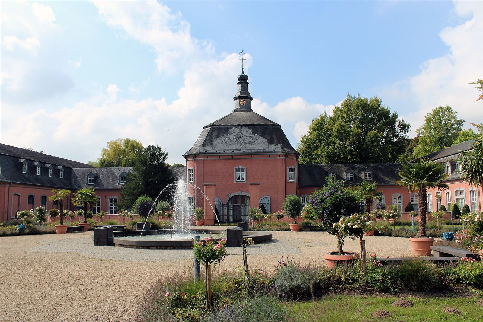 Schloss Wickrath in Mönchengladbach mit Springbrunnen und Kübelpflanzen im Sonnenschein