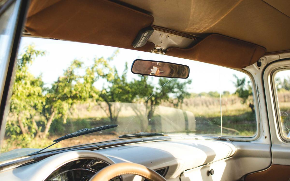Blick durch die Frontscheibe eines Oldtimers auf sonnige Obstbäume