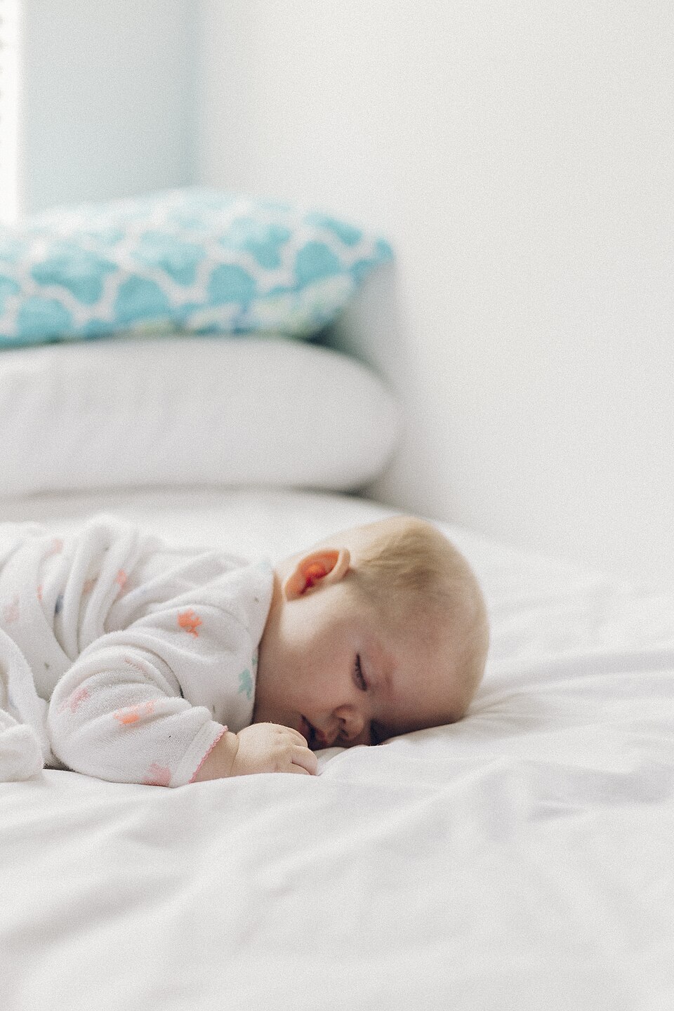 Ein Baby schläft auf einem weißen Bett