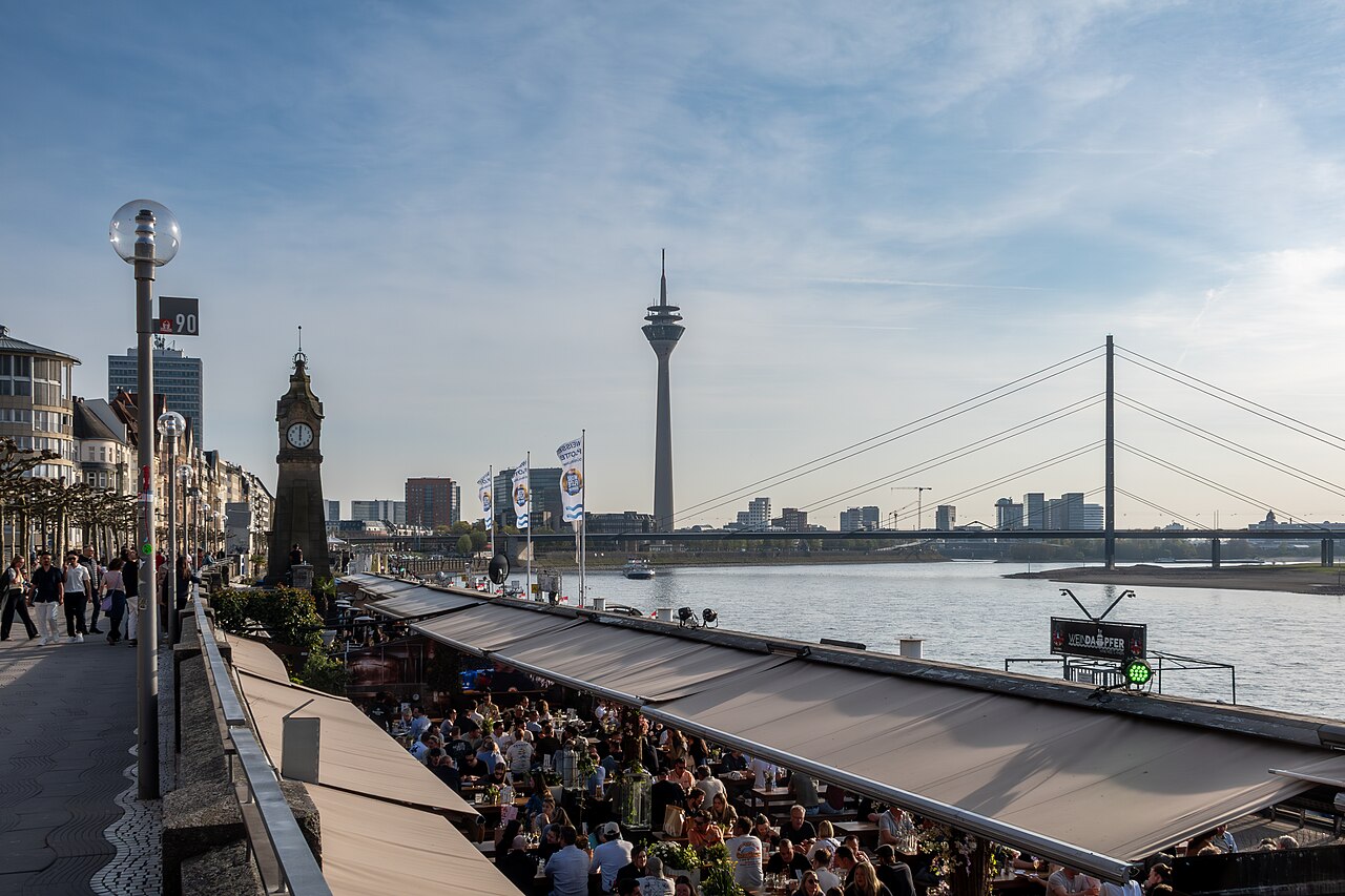 Rheinuferpromenade in Düsseldorf mit Rheinturm und Rheinkniebrücke im Abendlicht