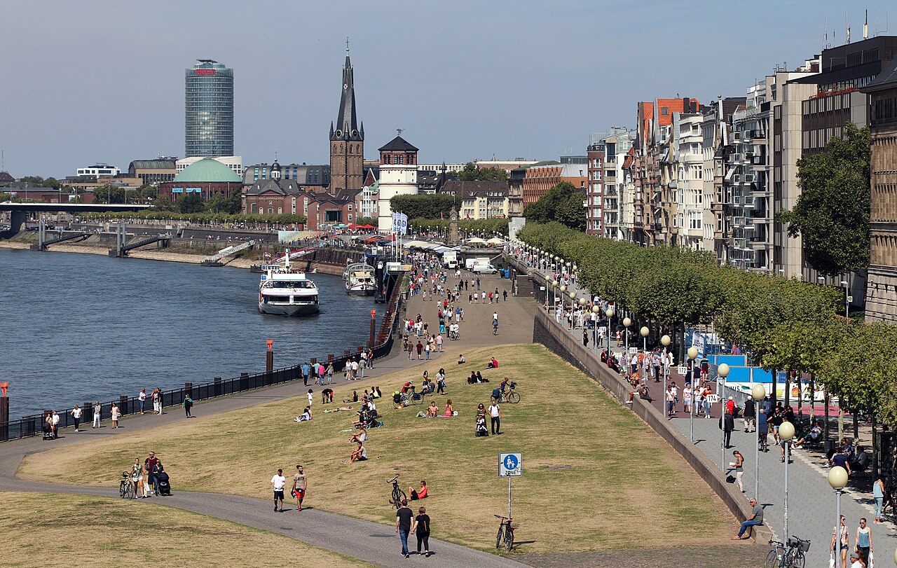 Menschen auf der Wiese an der Rheinuferpromenade in Düsseldorf an einem Sommertag
