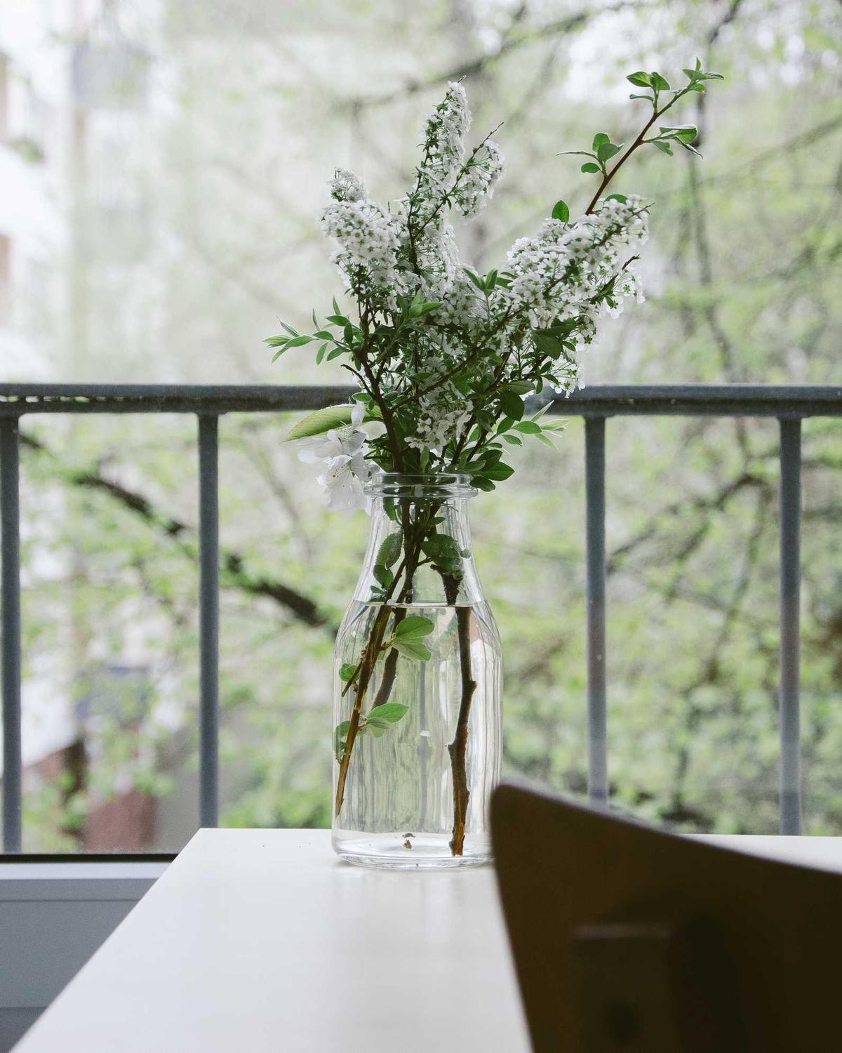 Kleiner Tisch mit Zweigen in einer Vase auf einem Balkon