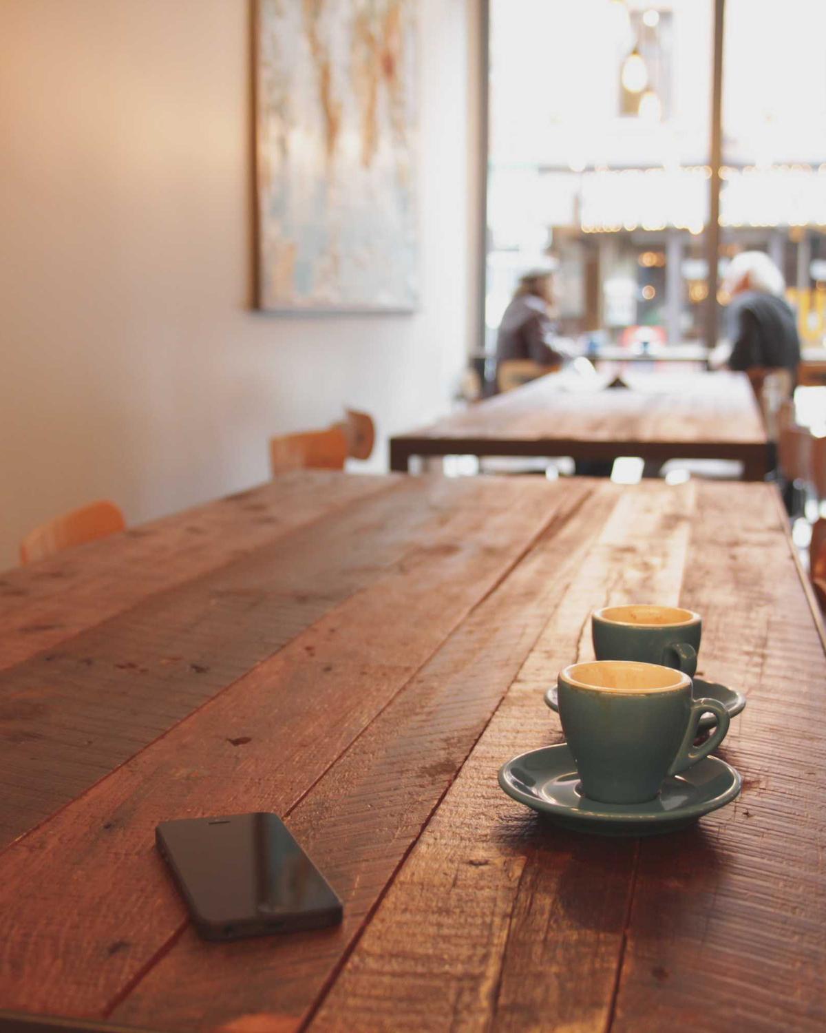 Kaffeetasse auf einem langen Holztisch in einem hellen Café